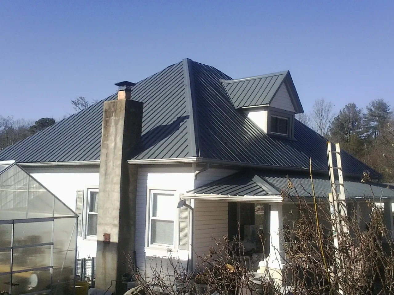 Dark blue standing seam metal roof on a white farmhouse with dormer — Slate & Tile Roof Repair by Roofing Brothers in Media