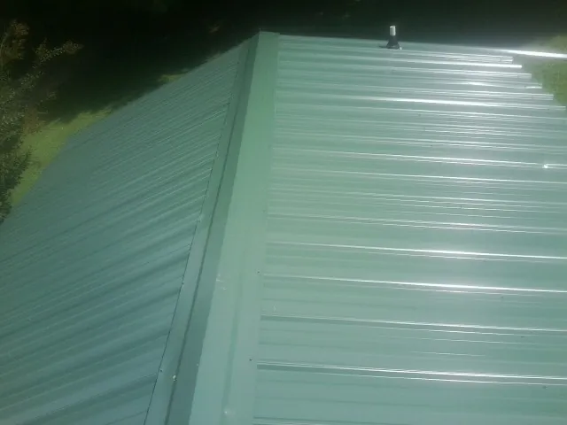 New green metal panels meeting at the ridge of a roof — Flat Roof Repair work by our crew in Media