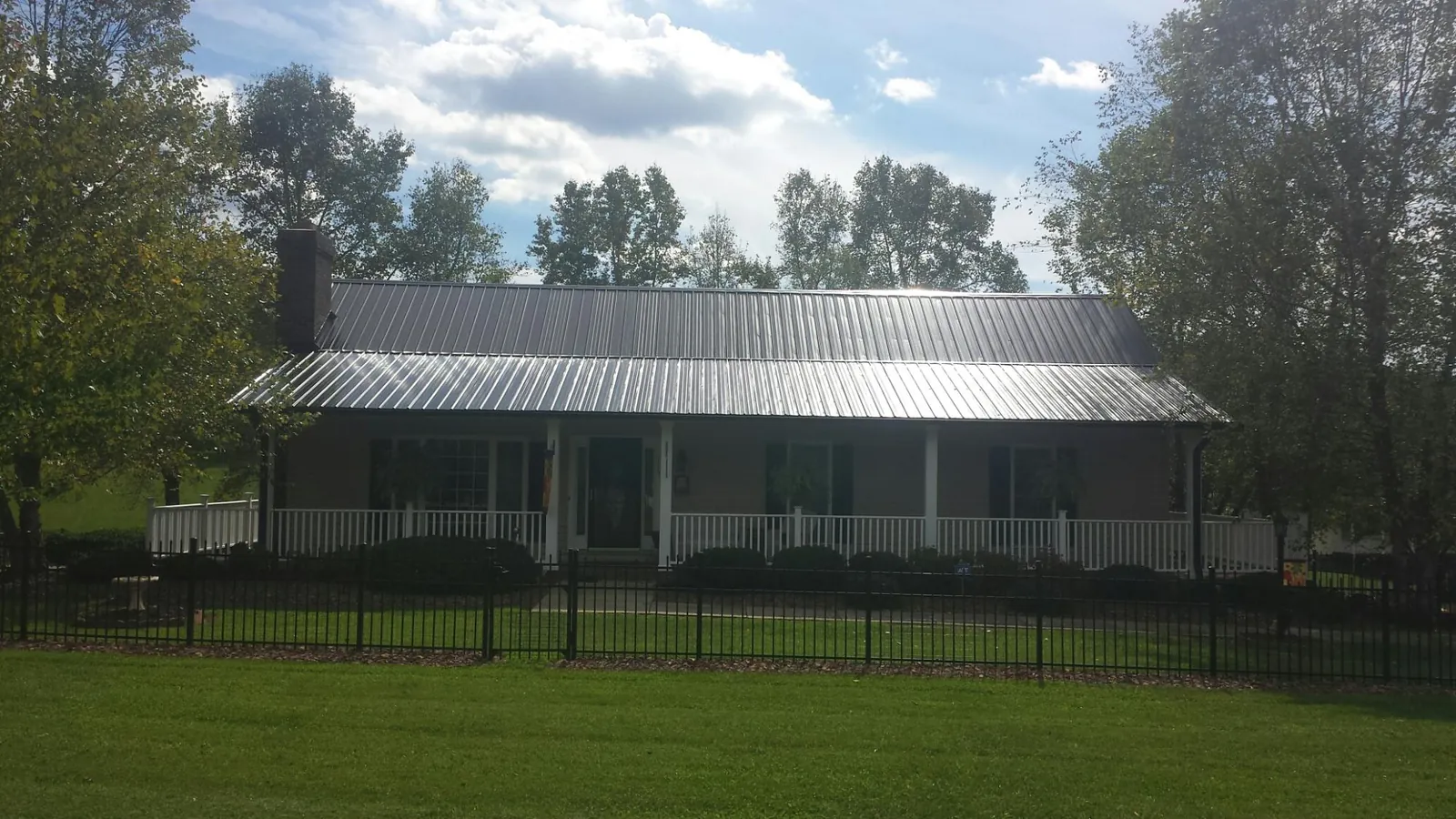 Gray metal roof on a brick ranch with a full width front porch — Gutter Guard Installation work by our crew in Media