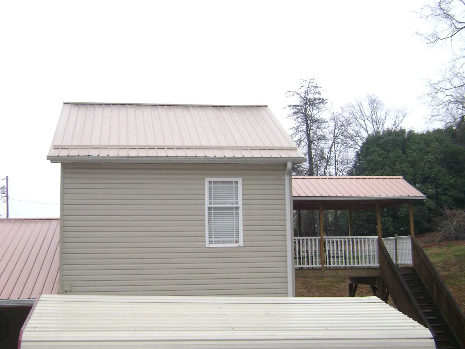 Tan metal roofs on a two story addition and attached porch, from a Roof Replacement job in Media