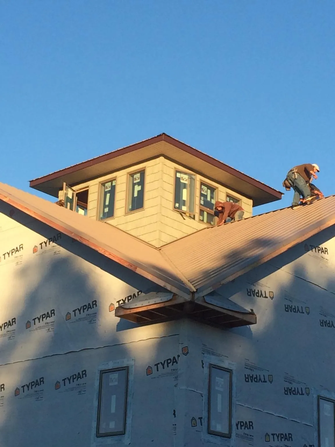 Roofers working around a rooftop cupola on a new metal roof at sunset — Roof Waterproofing in Media by Roofing Brothers